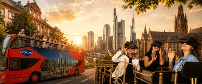 Red sightseeing bus in front of the Frankfurt skyline next to guests in VR headsets