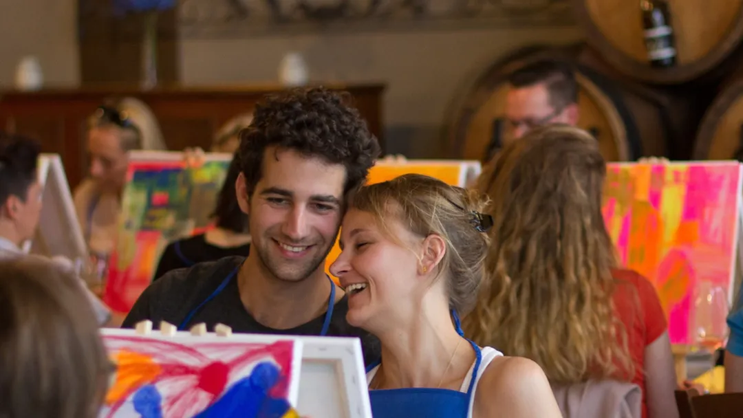Smiling couple surrounded by colorful abstract canvases