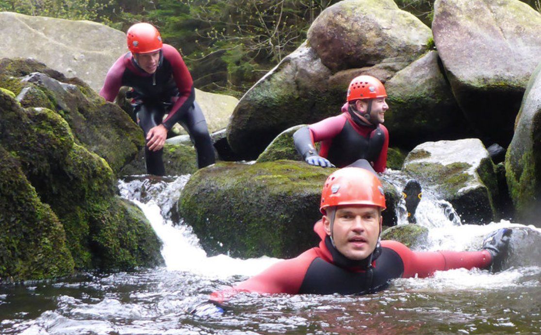 Three people with a helmet in a river