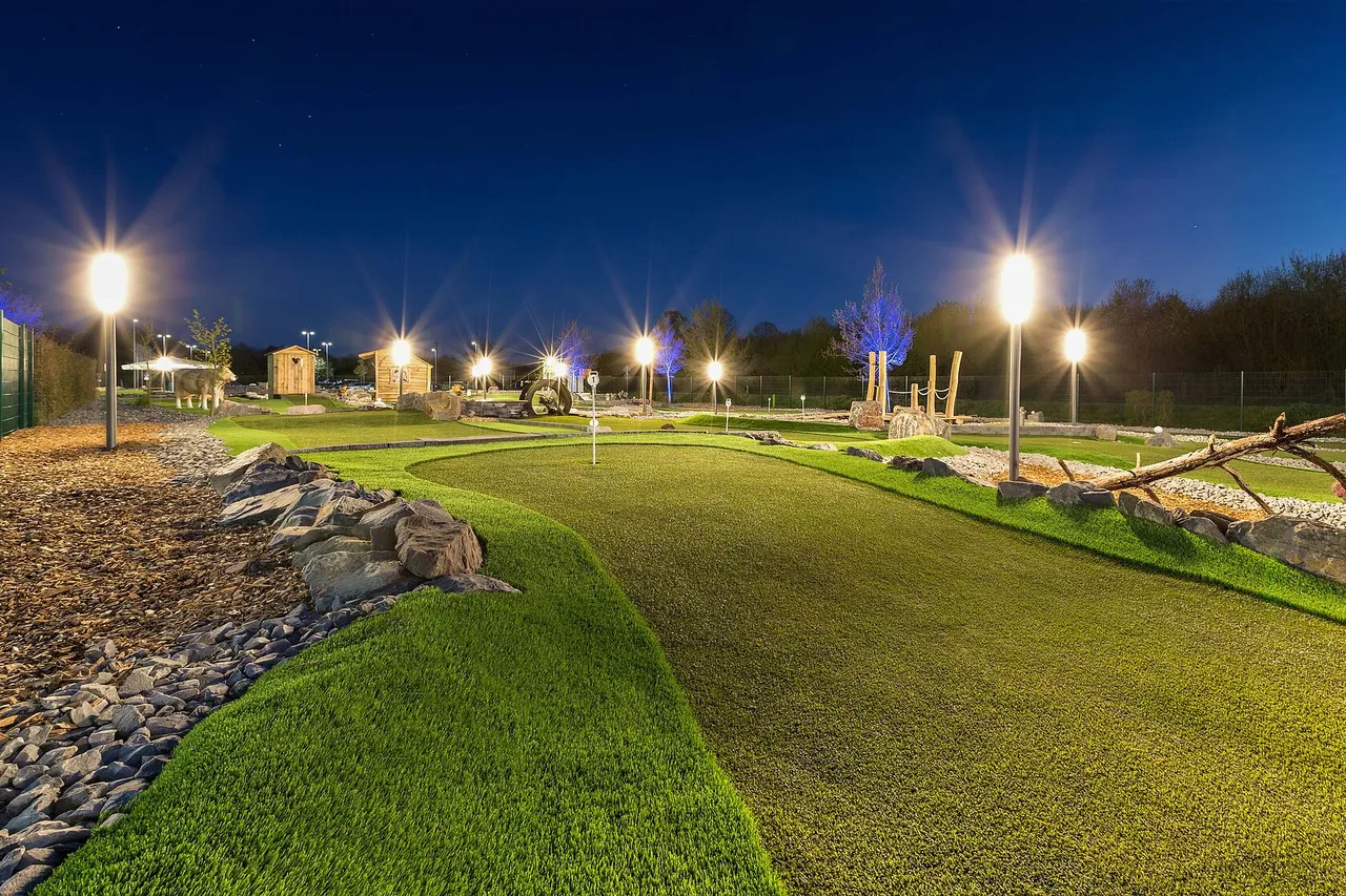 Illuminated adventure golf course at dusk under a deep blue sky