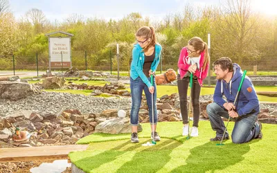 Father and two daughters putting together on an adventure golf course