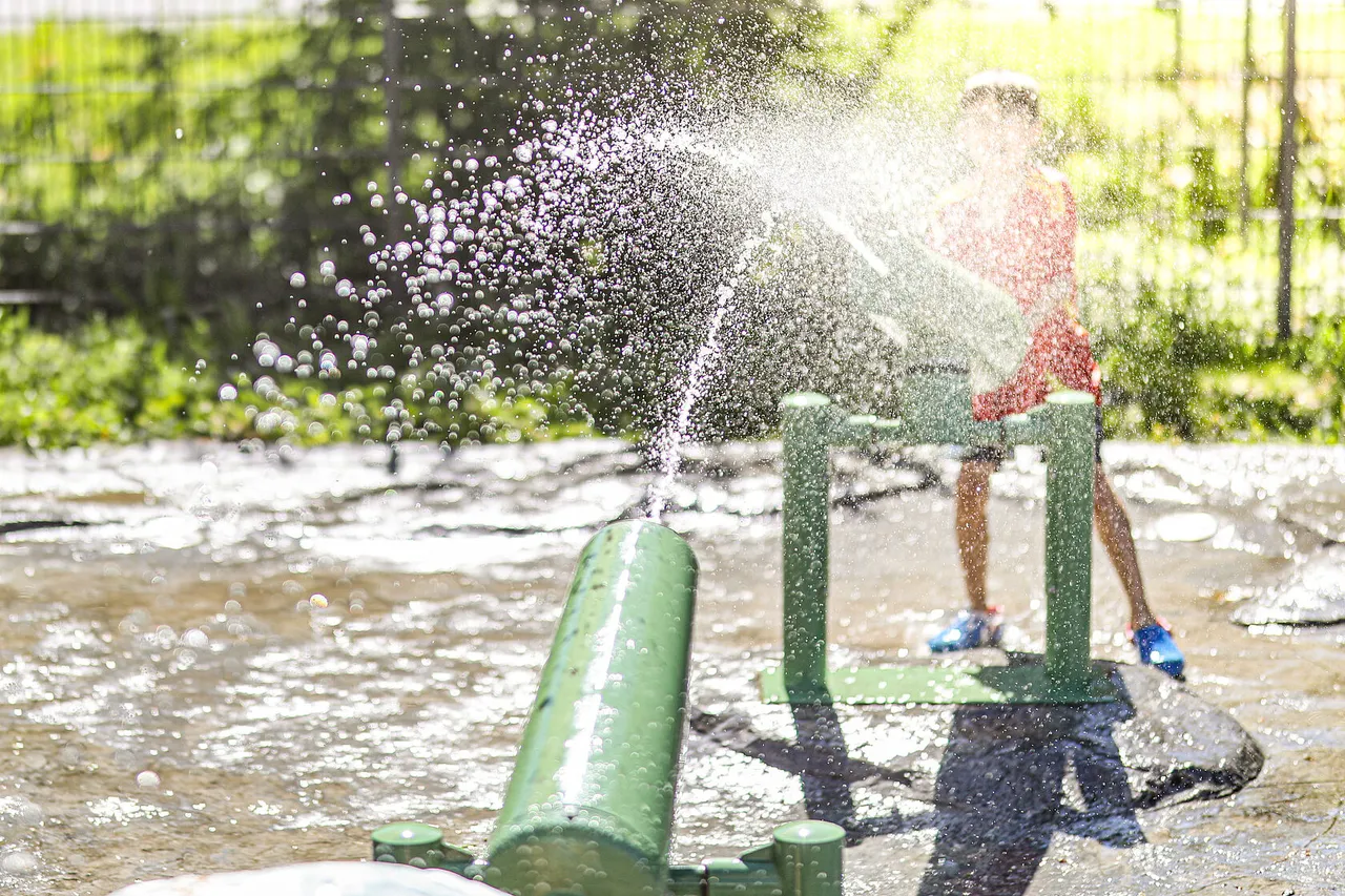 Child pumping water that splashes into a water play area