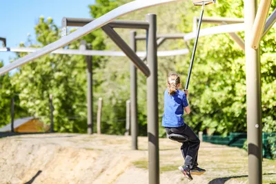 Child riding a mini zip line at an outdoor adventure playground