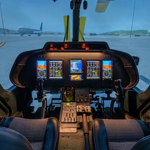 Agusta A109 helicopter simulator cockpit with digital displays and an airport scene ahead