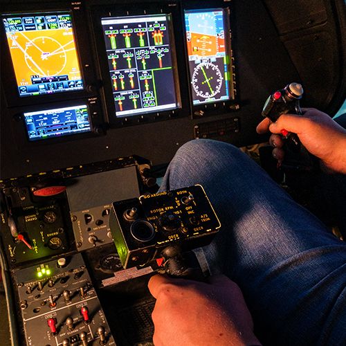 Pilot’s hand on the cyclic stick in front of the digital displays of the Agusta A109 simulator