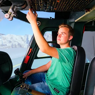Young pilot operating overhead switches in the Agusta A109 helicopter simulator cockpit