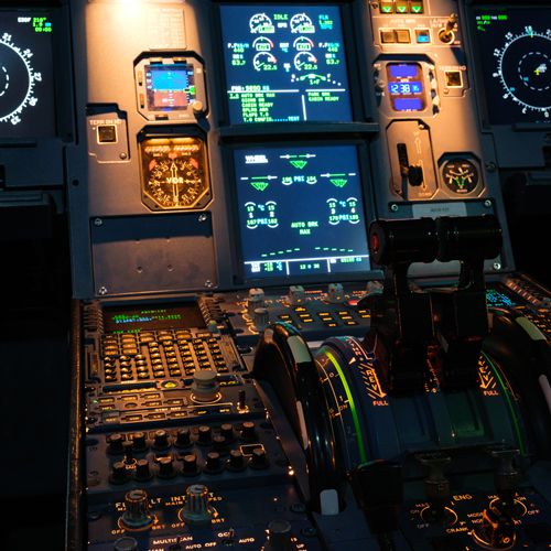 Center pedestal of the Airbus A320 simulator with thrust levers and illuminated cockpit displays
