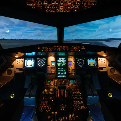 Illuminated Airbus A320 simulator cockpit with displays and a panoramic runway view