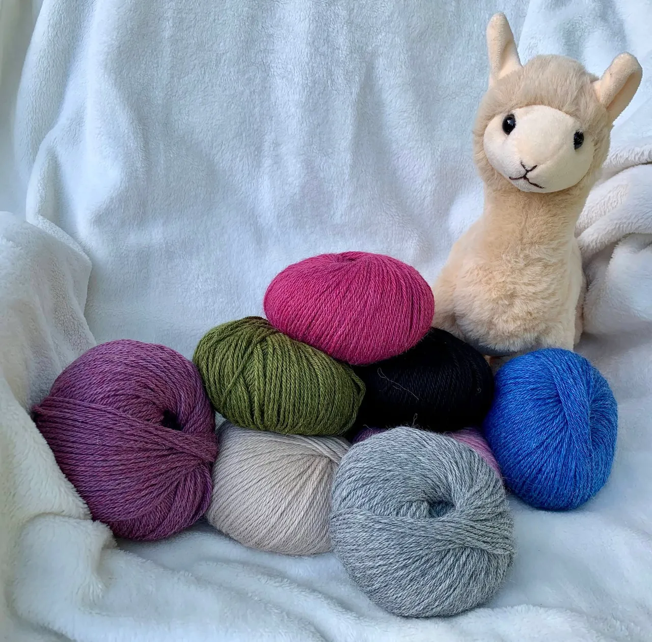 Balls of yarn in various colors and an alpaca figurine