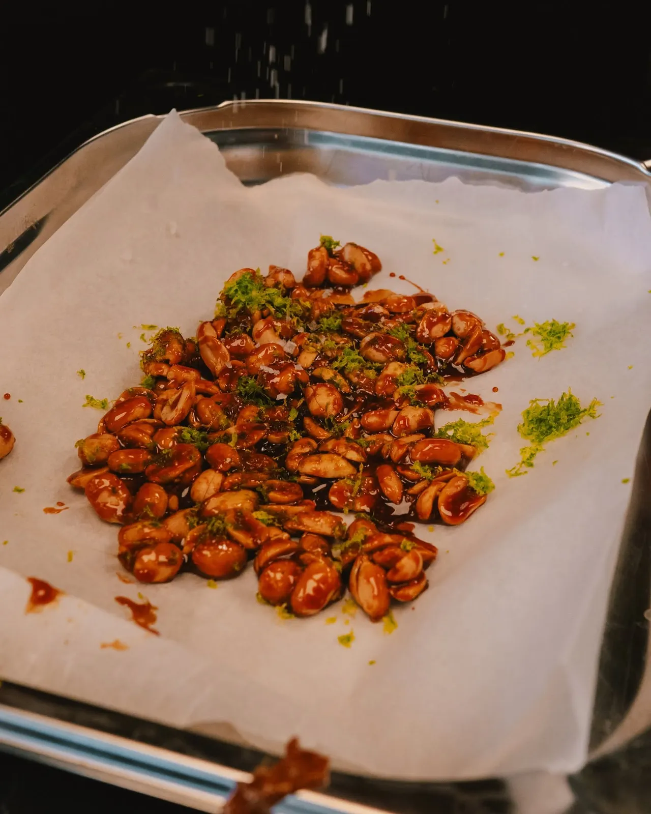 Glazed spicy nuts on baking paper with herbs