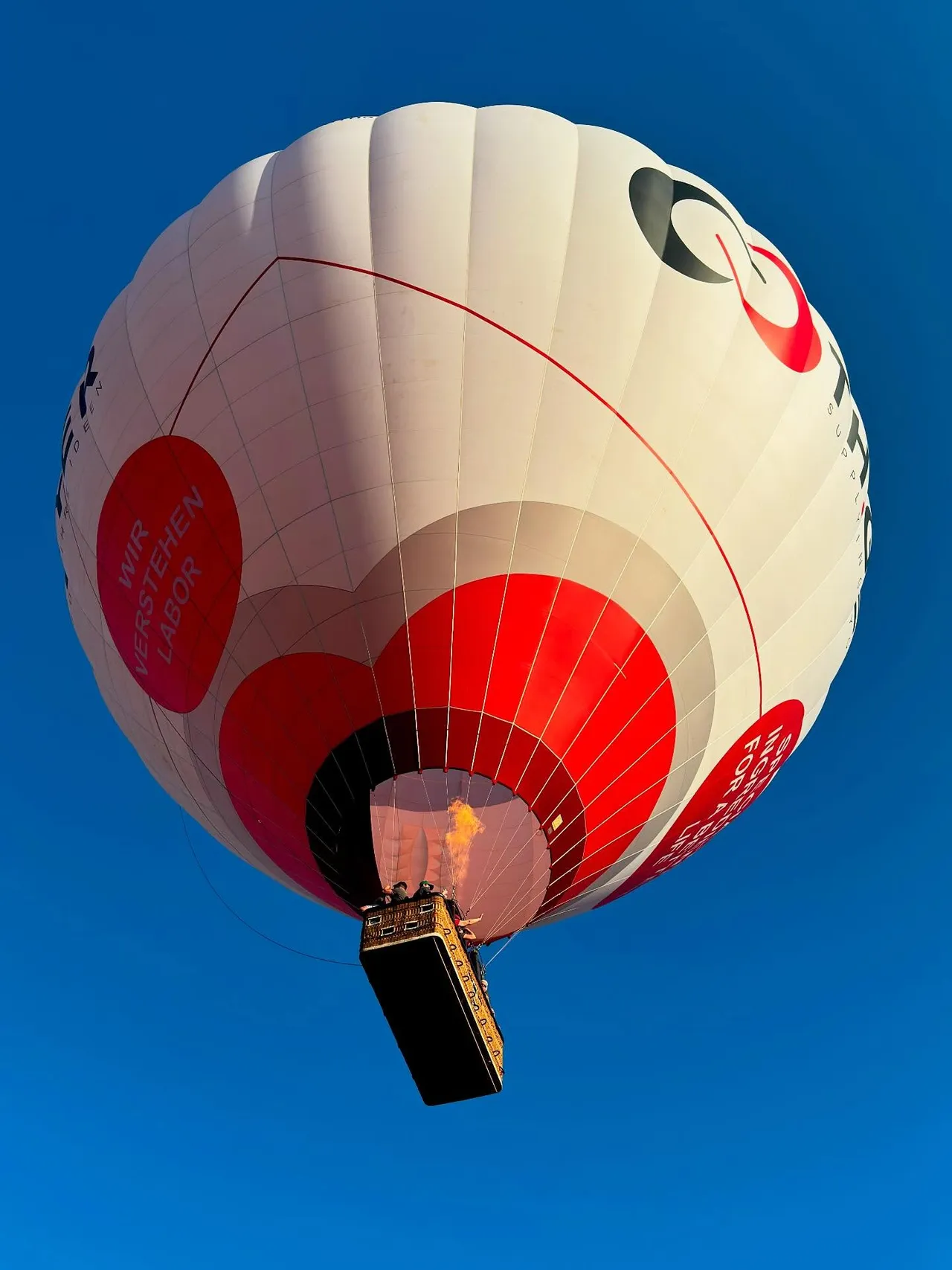 Hot air balloon seen from below against a deep blue sky