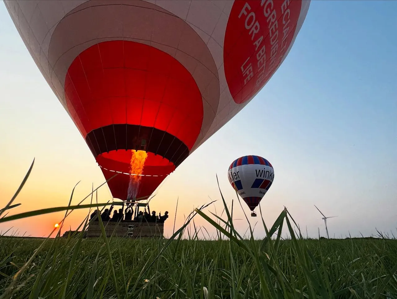 Hot air balloon ready for takeoff at sunset, with a second balloon in the sky