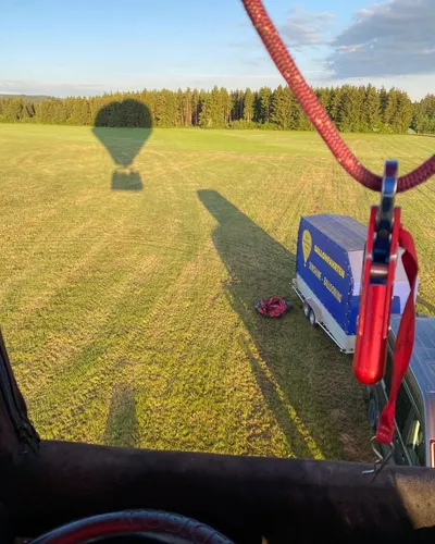 Shadow of the hot air balloon on a field, seen from the basket