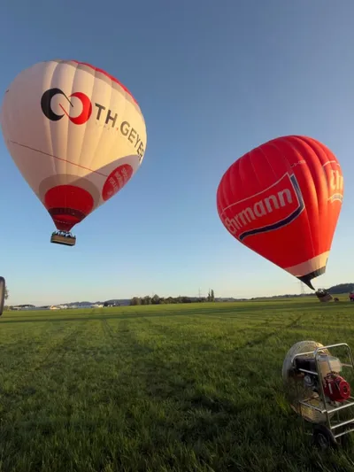 Two hot air balloons rising above a meadow