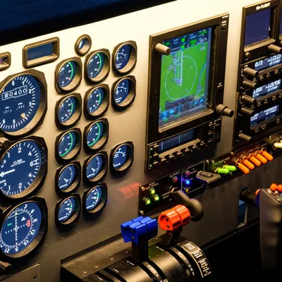 Close-up of the analog gauges, GPS screen and engine levers of the Baron 58 flight simulator