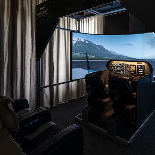 Overview of the Beechcraft Baron 58 simulator room with cockpit and curved projection screen