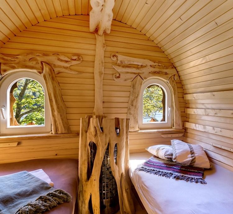 Barrel-shaped wooden bedroom with two arched windows, carvings and two beds