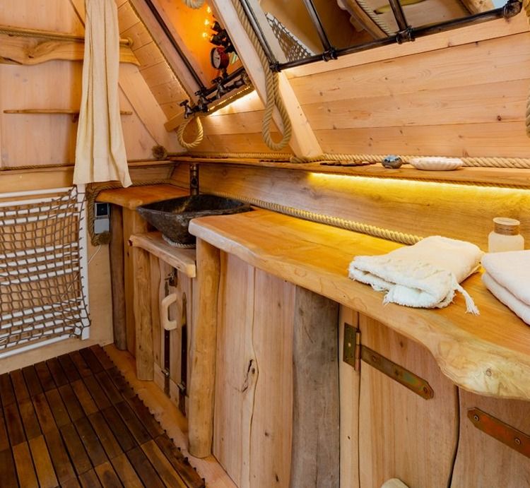 Rustic wooden bathroom with live-edge washstand, stone basin and towels
