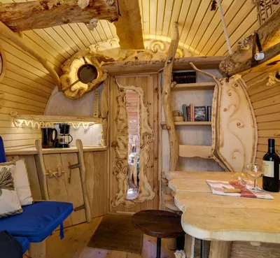 Living area inside a barrel treehouse with carved wooden table, bench and coffee corner