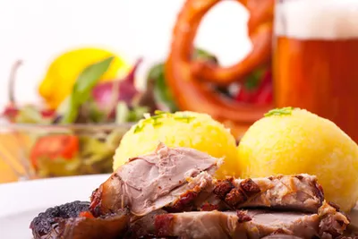 Roast pork with potato dumplings, a pretzel and a glass of beer