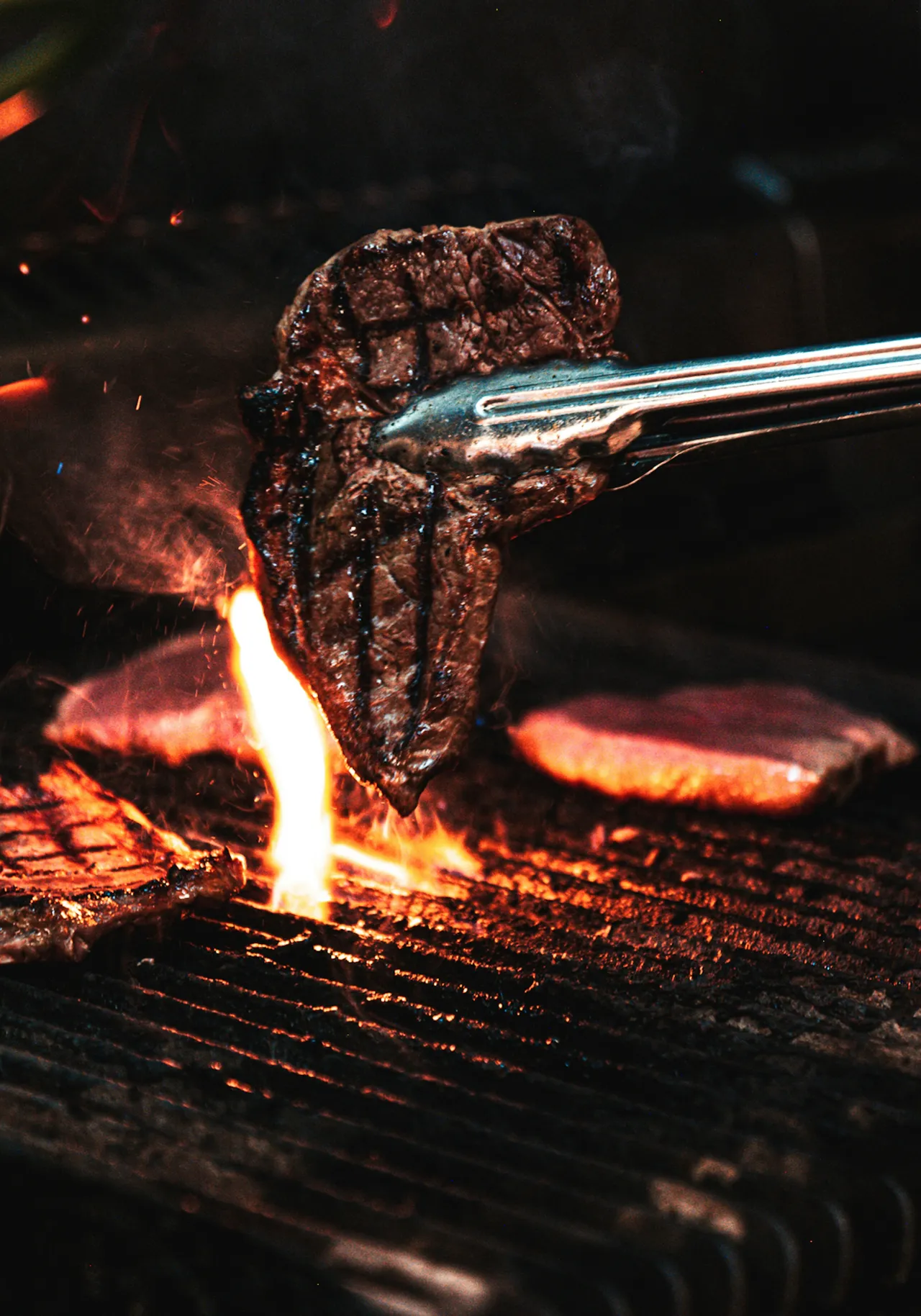 steak being lifted up from a charcoal crill