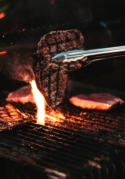 steak being lifted up from a charcoal crill