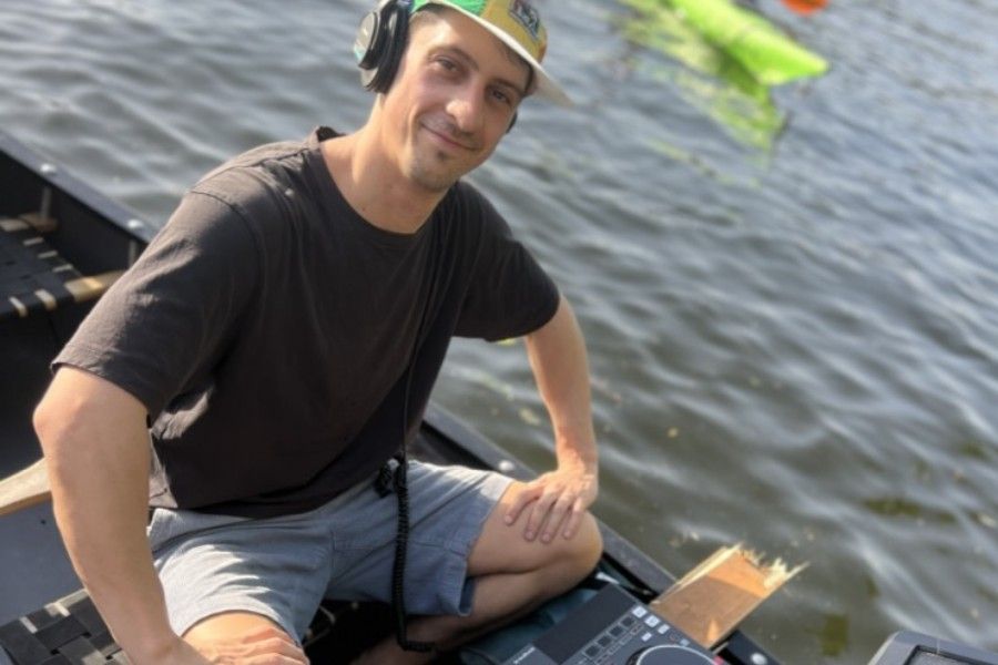 Smiling DJ wearing headphones behind his mixer on board during a canoe party tour in Berlin