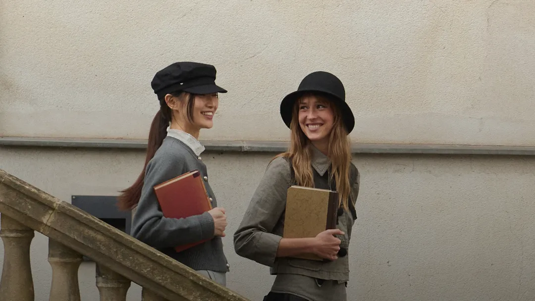 Two best friends walking down outdoor steps, smiling and holding books