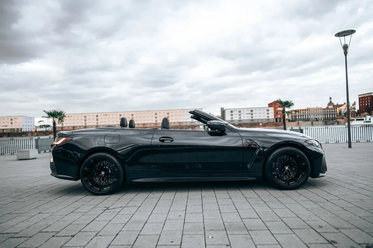 Side profile of a black BMW M4 Convertible with the roof down