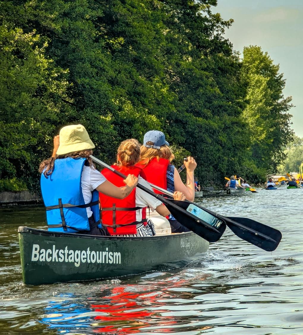 Family wearing life jackets paddling a canoe on the Spree river in Berlin on a sunny day