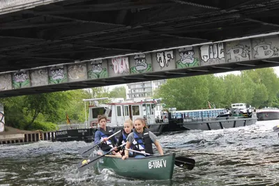 Paddlers in a canoe passing under a graffiti-covered railway bridge on the Spree in Berlin