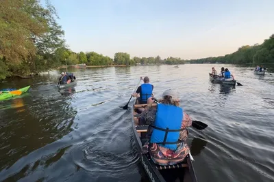 View from a canoe of several boats paddling down the tree-lined Spree river in Berlin