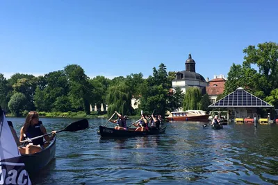 Canoes with paddlers on the water in front of the baroque Köpenick Palace in Berlin