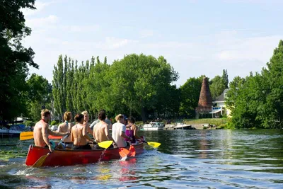 Paddlers in a red canoe on the water in Köpenick, Berlin, with a historic brick tower behind