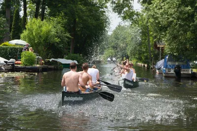 Paddlers splashing water between canoes on a leafy canal in Neu Venedig, Berlin
