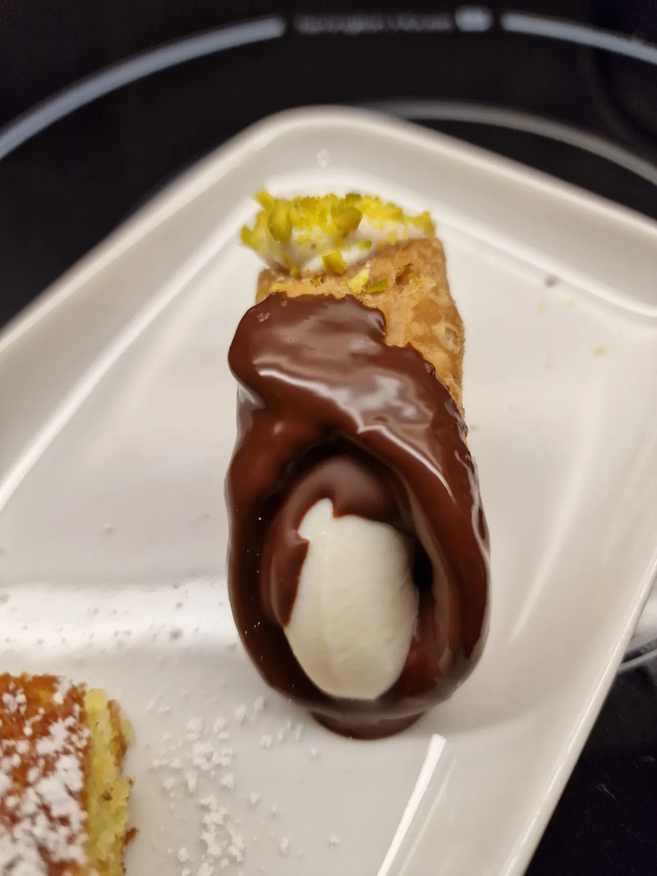 Sicilian Canolo with ricotta filling with chocolate and pistaccio on a plate