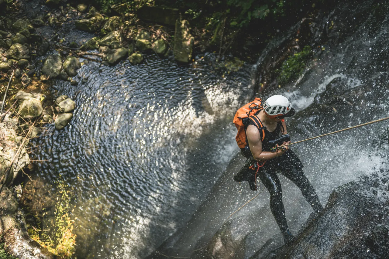 Participant rappelling down a waterfall during a canyoning adventure in the Austrian Alps.
