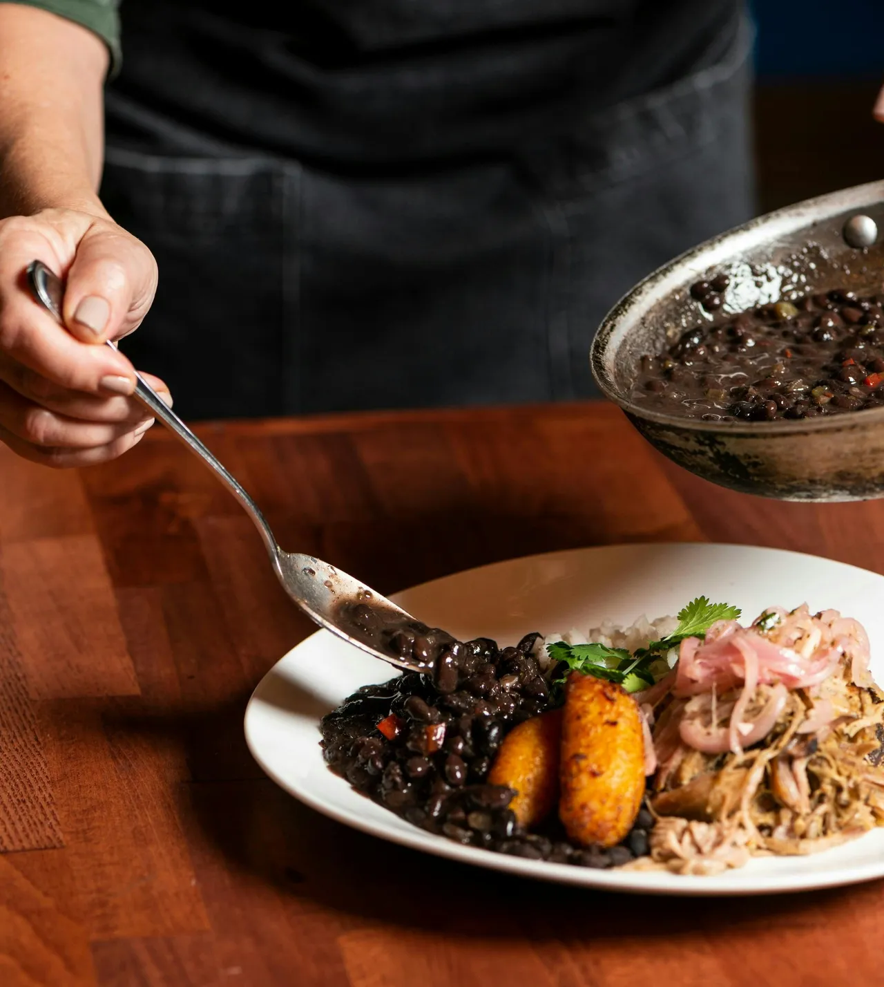 A plate of seasoned Caribbean jerk chicken served alongside rice and peas, grilled plantains, and a side salad.