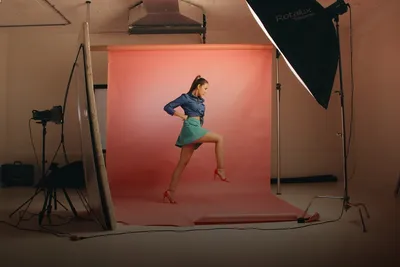 Photo shoot: model posing in a photo studio with a pink backdrop