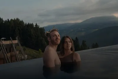 Wellness & short breaks: couple relaxing in an infinity pool with a mountain view