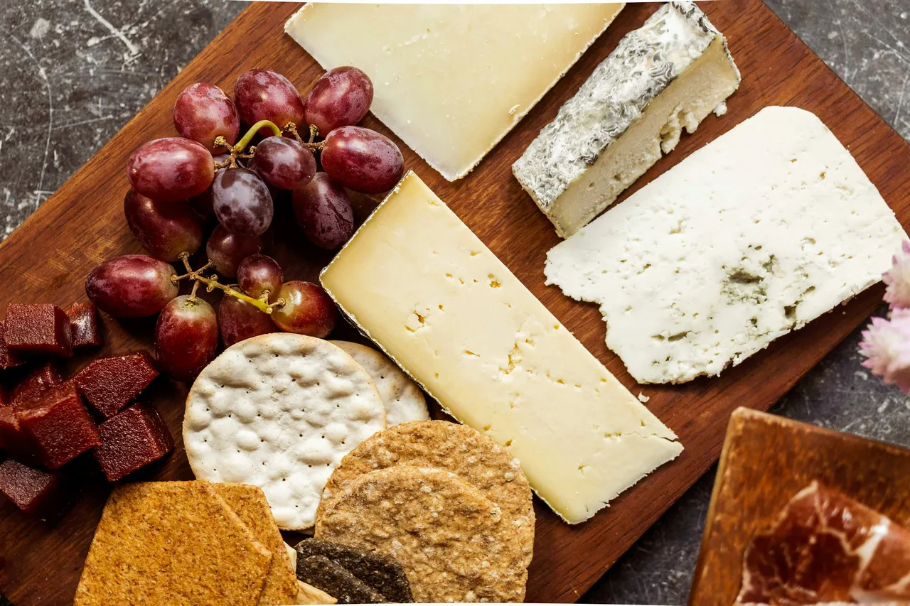 A variety of cheeses on a wooden cutting board