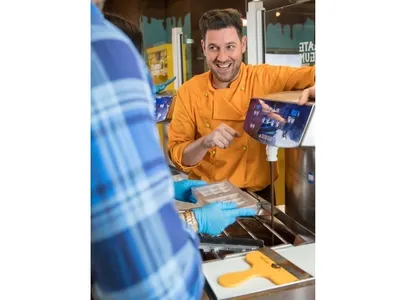 A man explaining a machine that pipes chocolate into a praline mold
