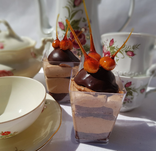 Two desserts with chocolate in cups on a table