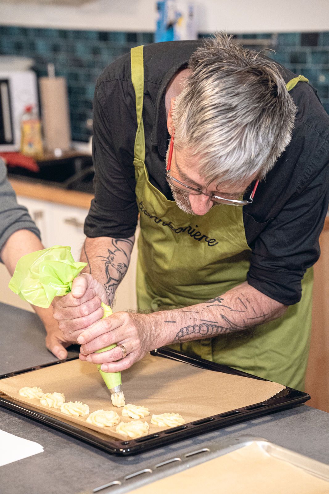 Participant in an apron piping biscuit dough onto a baking tray