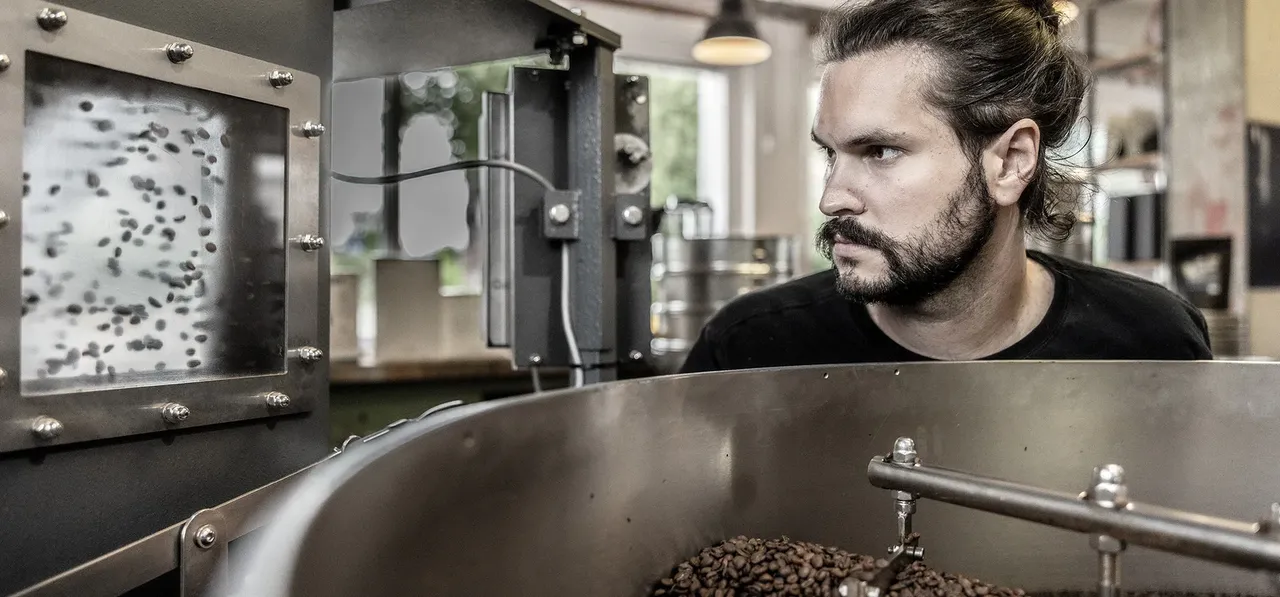 A man looking at a coffee roaster