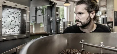 A man looking at a coffee roaster