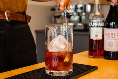 A person preparing a cocktail with Campari
