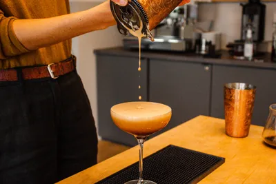 A person preparing an Espresso Martini cocktail
