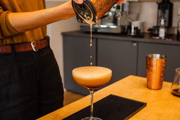 A person preparing an Espresso Martini cocktail