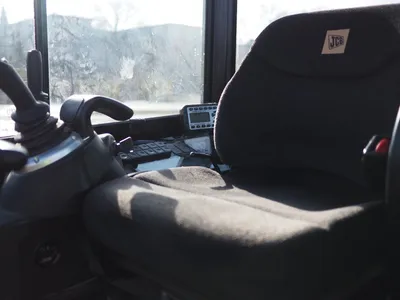 View inside the cab of a construction machine with joystick controls and driver’s seat